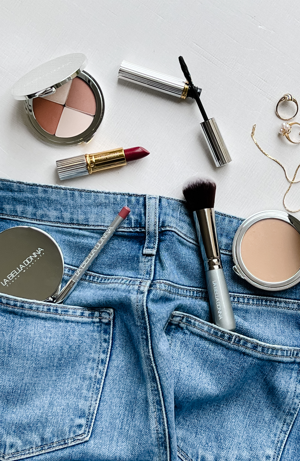 Assortment of La Bella Donna products shown over a pair of jeans